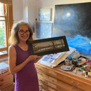 Janet Johnson with framed landscape painting of nocturne